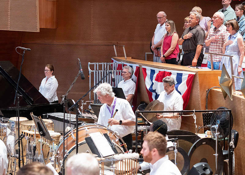 David Hiller, as a face in the crowd (plaid shirt), stands for the national anthem