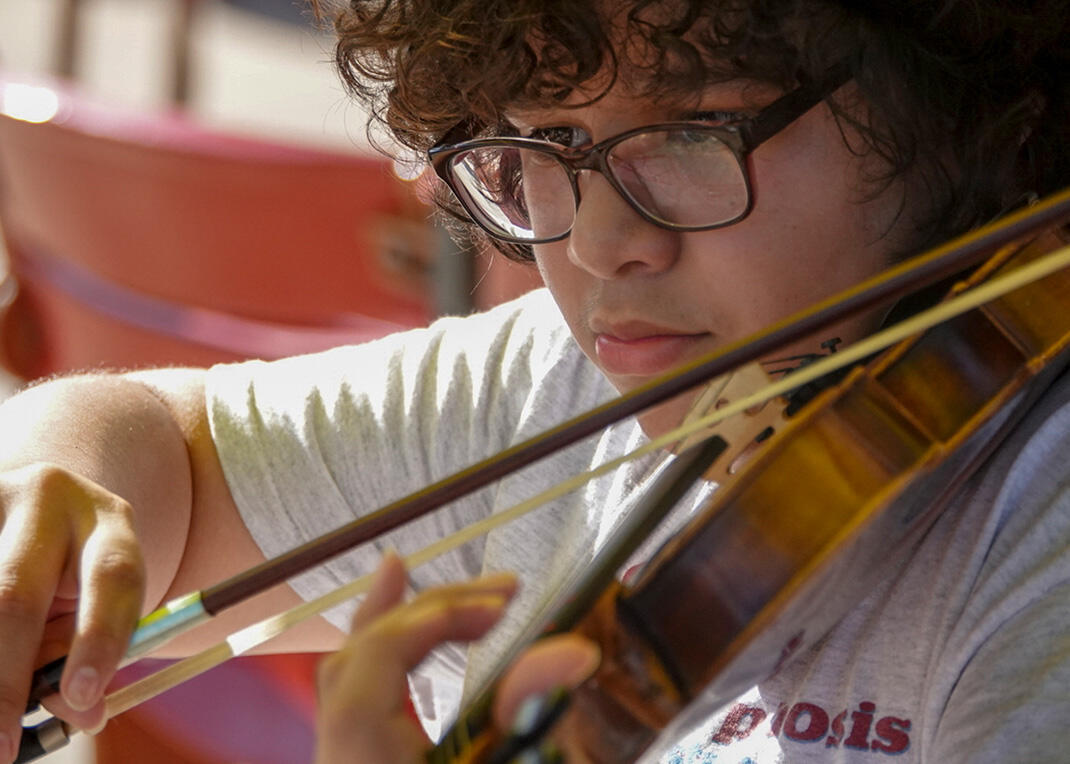 A young fiddler from the Chicago Metamorphosis Orchestra Project performs in the Pritzker Pavilion ahead of a Grant Park Orchestra concert