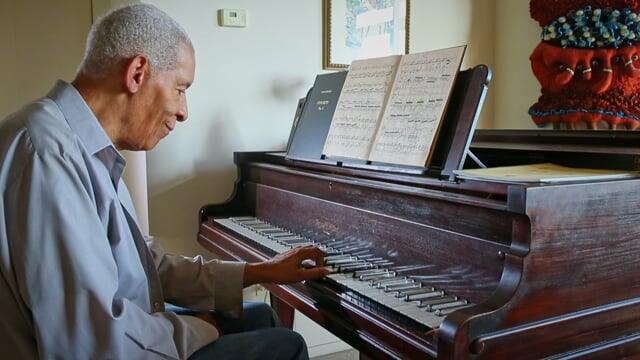 Norman Malone practices the piano in his Hyde Park living room