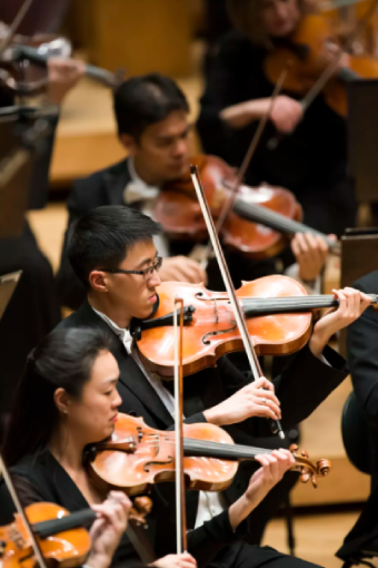 Chicago Symphony Orchestra Viola Danny Lai (center, pictured with CSO Violin Sylvia Kilcullen) performs during a CSO concert at Orchestra Hall in 2019. © Todd Rosenberg Photography