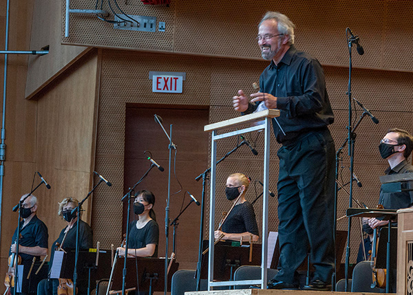 Carlos Kalmar takes a bow before a masked orchestra